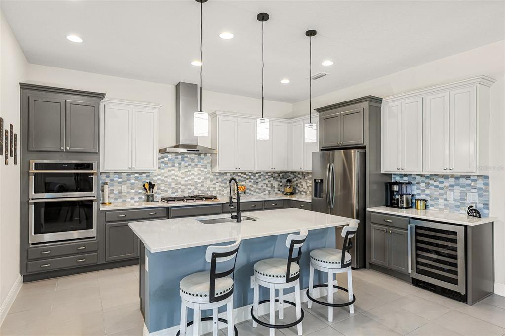 A modern kitchen features two-toned gray and white cabinetry, a central island, and stainless appliances — 4316 SEA MARSH PLACE, PARRISH, FL