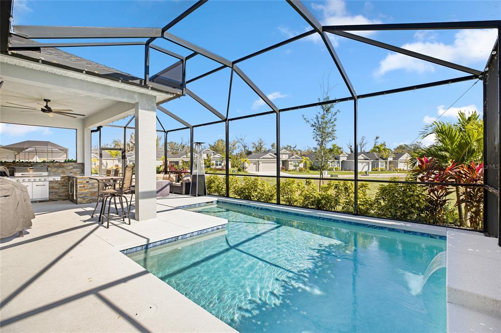 A screened-in patio features a swimming pool, a water feature, and an outdoor kitchen area — 4316 SEA MARSH PLACE, PARRISH, FL