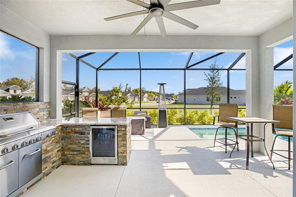 A covered outdoor kitchen and patio area features a grill, beverage cooler, and pool view — 4316 SEA MARSH PLACE, PARRISH, FL