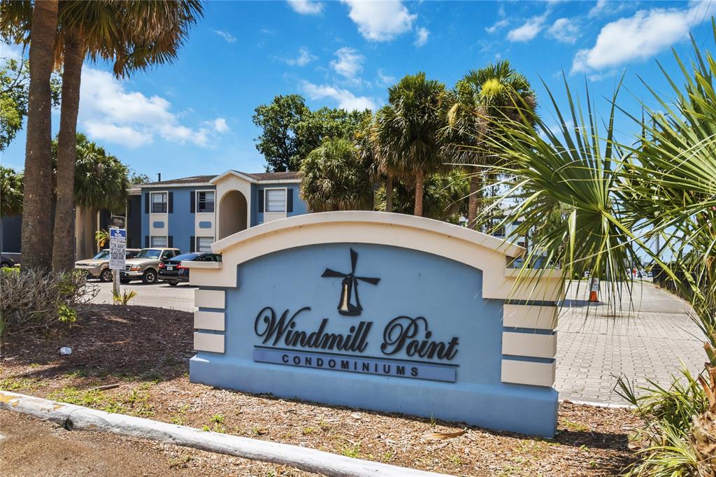 A blue monument sign for Windmill Point Condominiums stands before a multi-story apartment building — 2569 N ALAFAYA TRAIL UNIT 133, ORLANDO, FL
