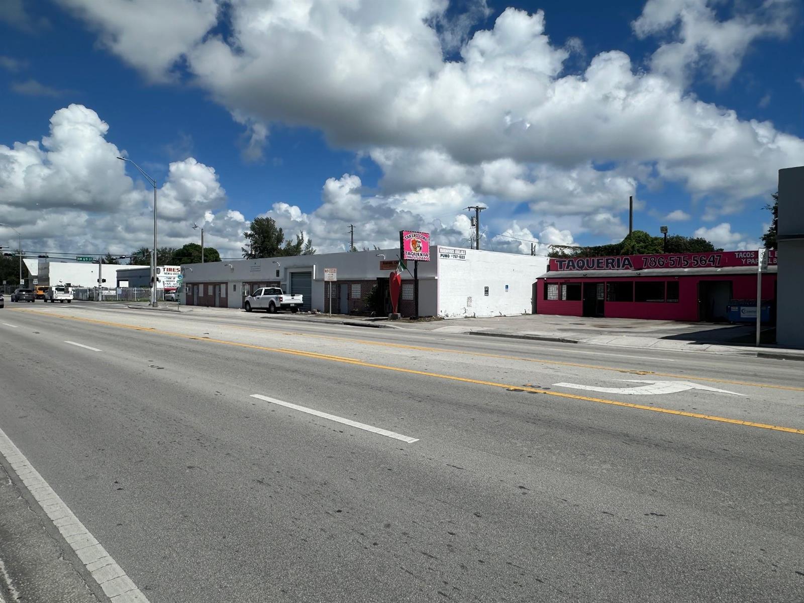 A street-level view of a white and pink commercial building with a taqueria sign — 6815 NW 7th Avenue, Miami FL 33150, MIAMI, FL