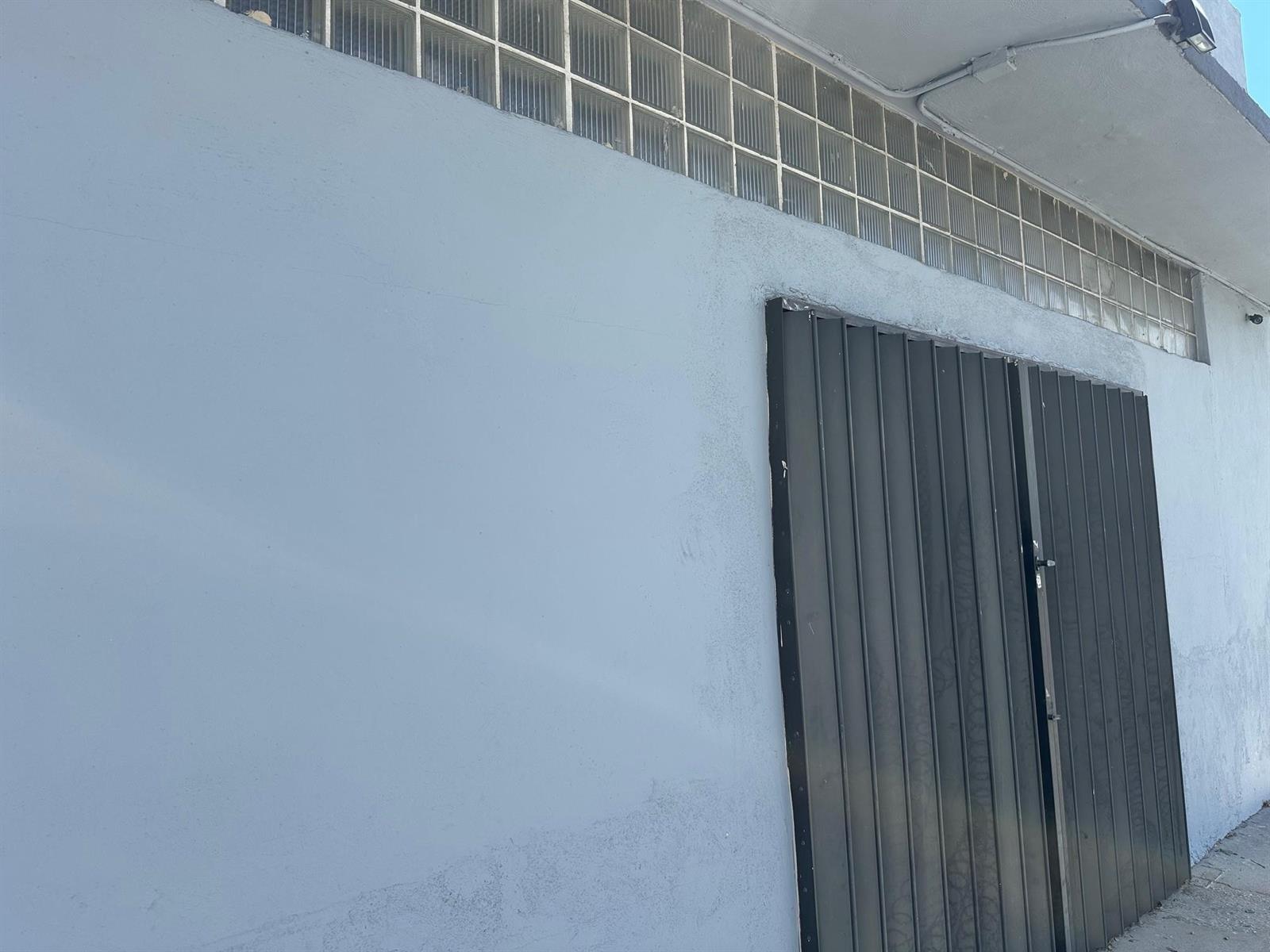 A light blue exterior wall features a dark metal gate and a row of glass blocks — 6815 NW 7th Avenue, Miami FL 33150, MIAMI, FL