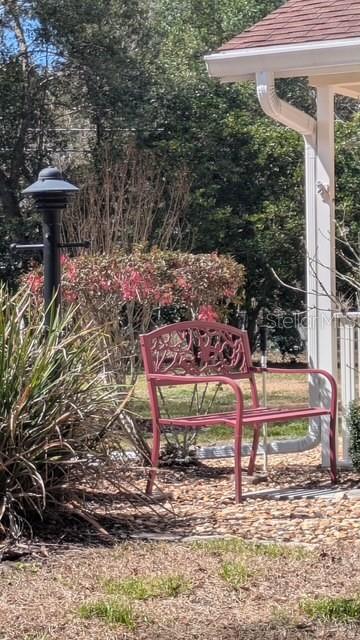 A red metal bench sits on a gravel area next to a porch post — 901 W PENN HILLS COURT UNIT 901, BEVERLY HILLS, FL