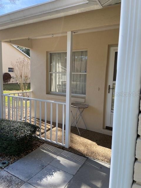 A covered porch features a white railing, a small table, and a glass-paneled door — 901 W PENN HILLS COURT UNIT 901, BEVERLY HILLS, FL