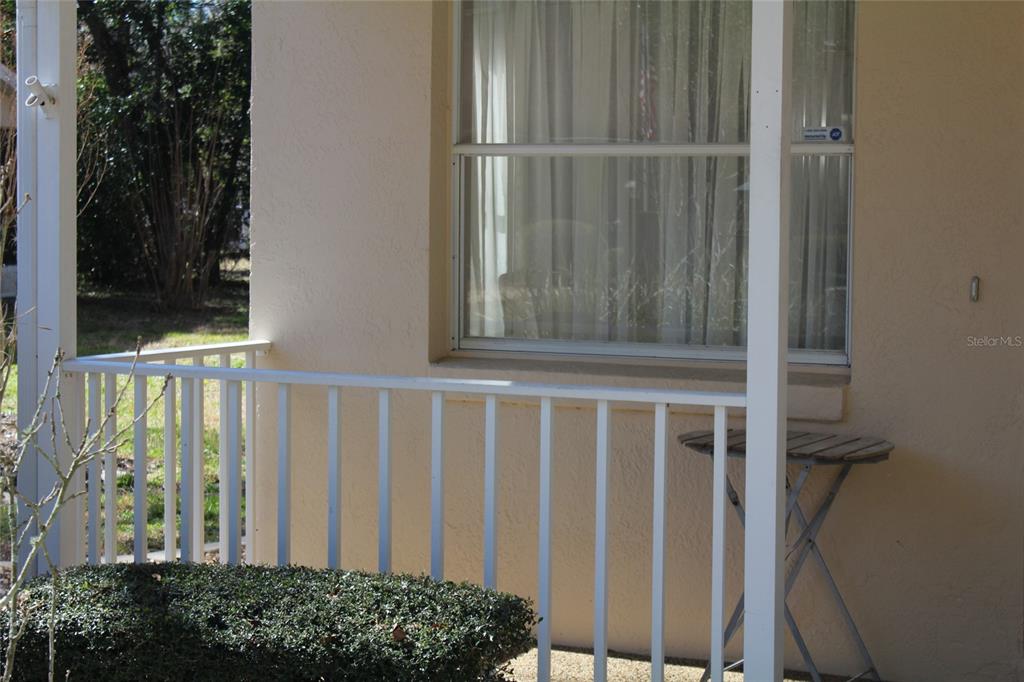 A beige exterior wall features a window, a white railing, and a small folding table — 901 W PENN HILLS COURT UNIT 901, BEVERLY HILLS, FL