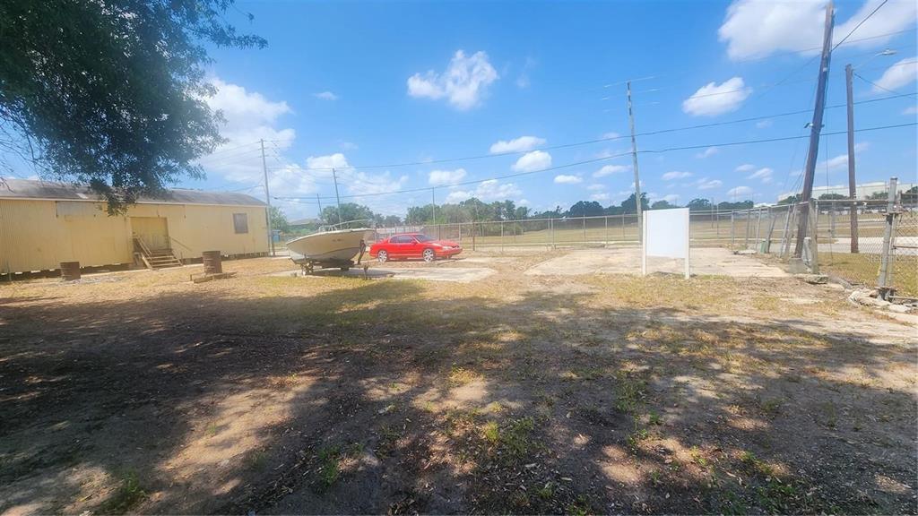 An outdoor lot features a small yellow building, a boat on a trailer, and a car — 620 DOCTORS LANE, LAKE WALES, FL