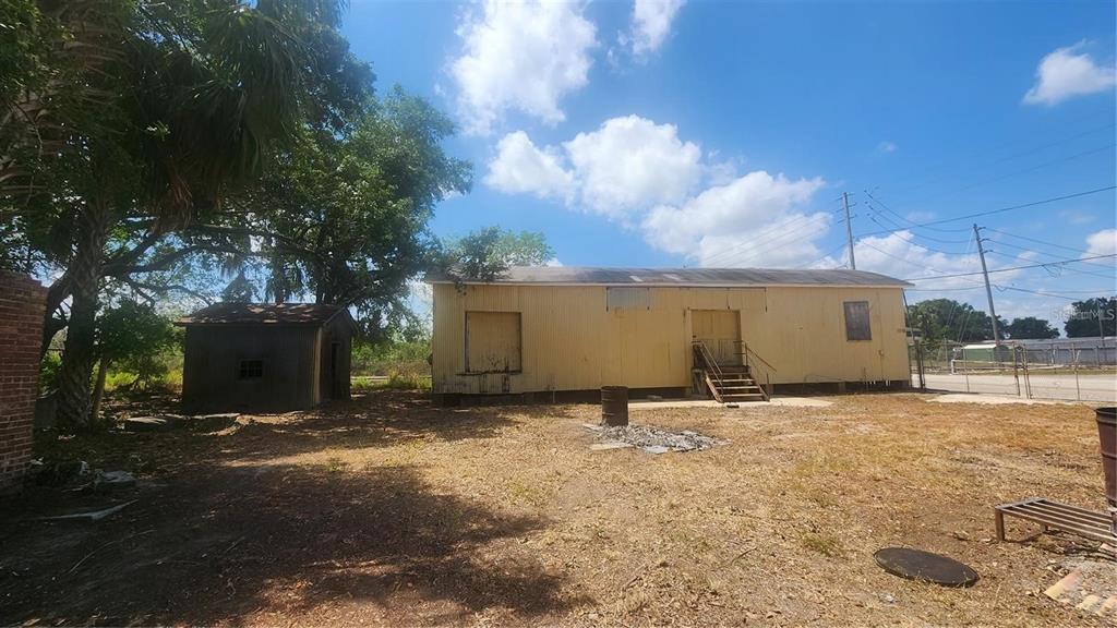 A yellow metal-sided building stands on a dirt lot next to a small shed — 620 DOCTORS LANE, LAKE WALES, FL