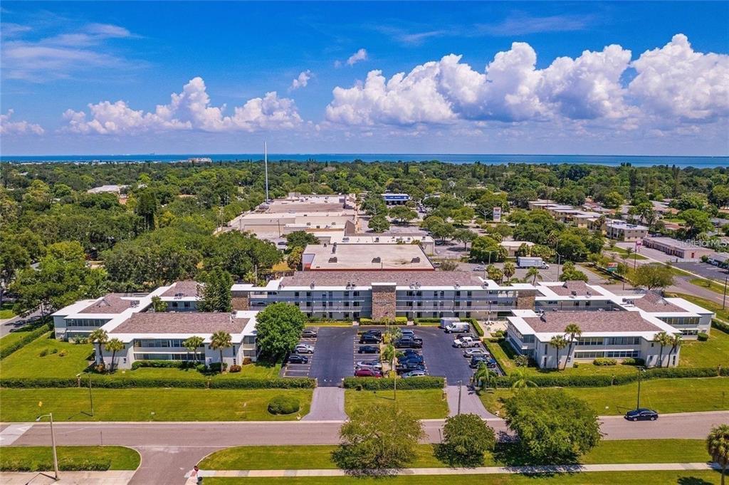 An aerial view of a multi-story apartment complex with a parking lot and surrounding greenery — 6100 12TH STREET S UNIT 107, ST PETERSBURG, FL