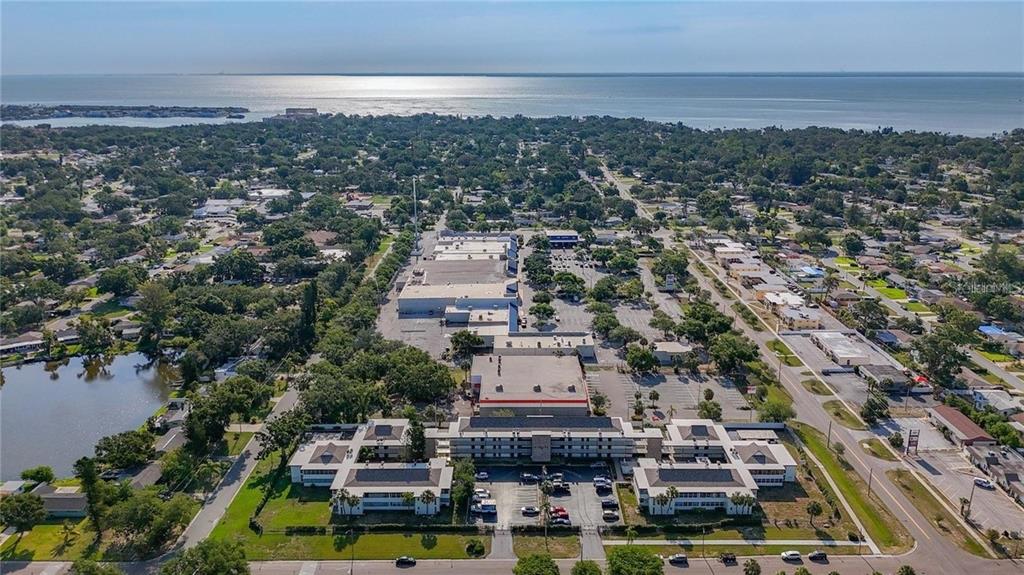 An aerial view shows a commercial complex with a large parking lot near the coast — 6100 12TH STREET S UNIT 107, ST PETERSBURG, FL