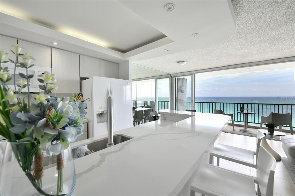 A balcony with a small table and two chairs overlooks the ocean through sliding doors — 4745 ISLA VERDE AVENUE UNIT 17G, CAROLINA, PR