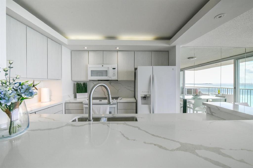 A modern living room with a glass dining table, gray sofa, and balcony overlooking the ocean — 4745 ISLA VERDE AVENUE UNIT 17G, CAROLINA, PR