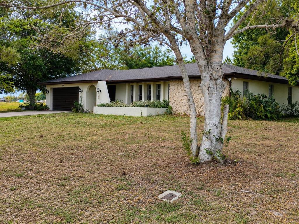 A single-story house with a stone facade, a garage, and a large tree in front — 7317 LIME TREE COURT, SEBRING, FL