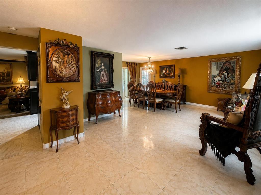 A dining room and living area feature mustard-colored walls, tiled floors, and ornate traditional furniture — 7317 LIME TREE COURT, SEBRING, FL