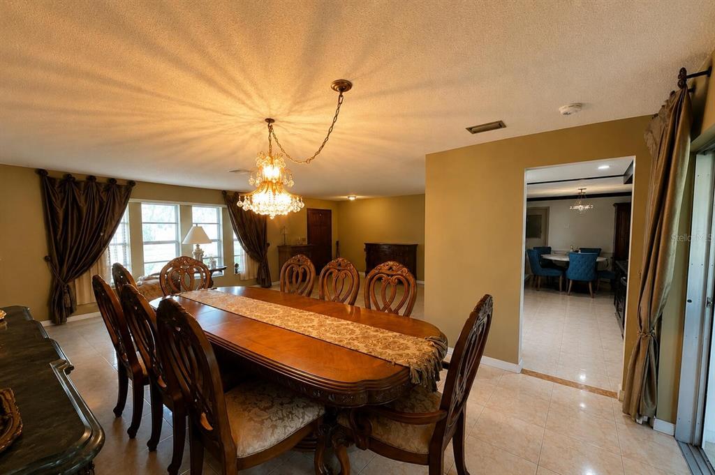 A dining room features a large wooden table, ornate chairs, and a crystal chandelier — 7317 LIME TREE COURT, SEBRING, FL