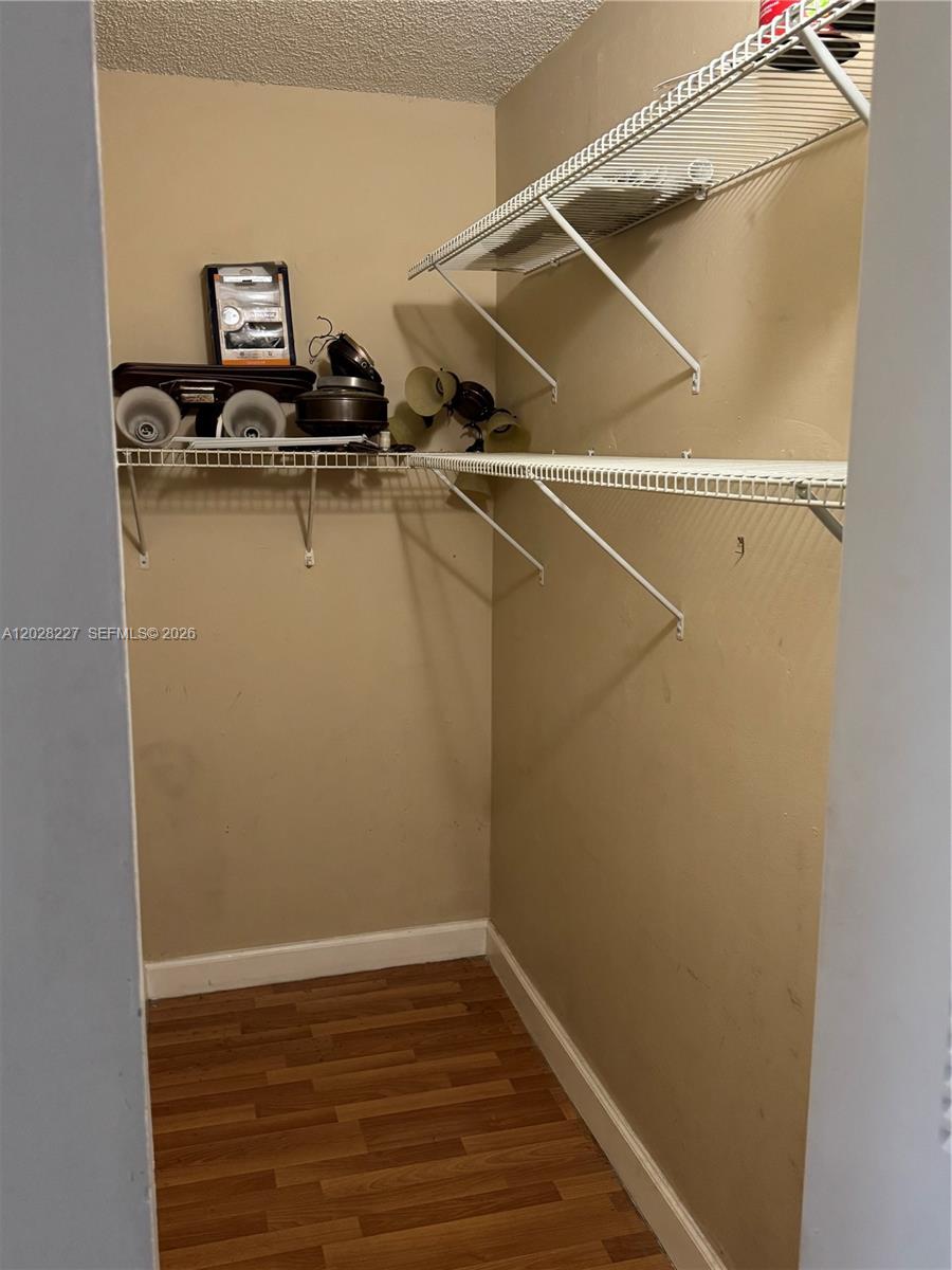 A small closet features wire shelving, tan walls, and wood-look laminate flooring — 6195 NW 186th St # 303, Hialeah FL 33015, HIALEAH, FL