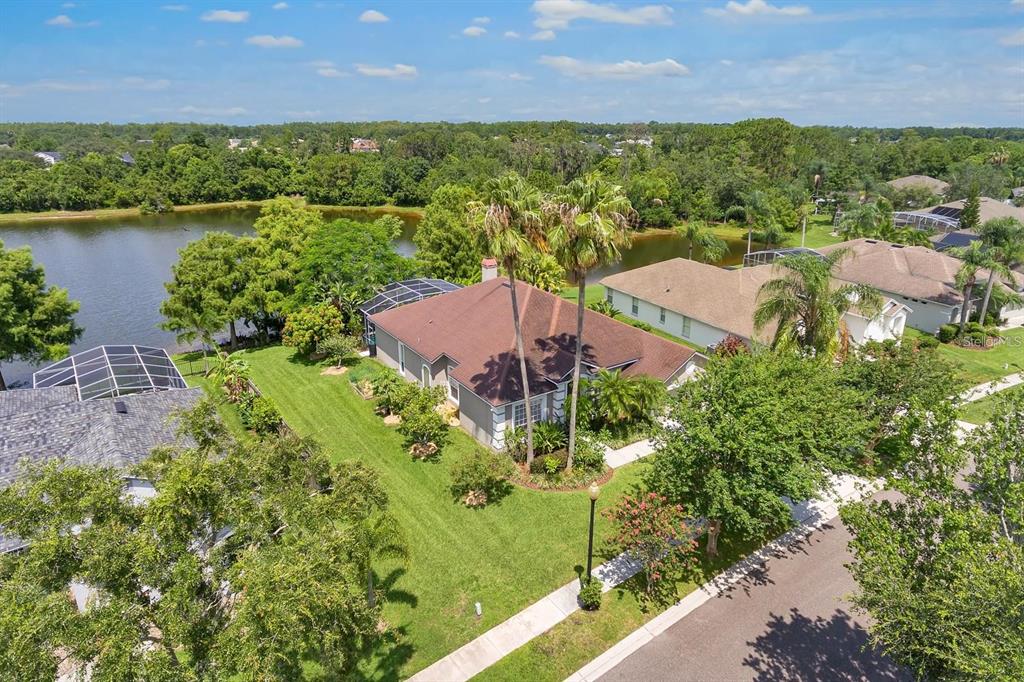 An aerial view shows a single-story house with a brown roof beside a lake — 13903 BLUEWATER CIRCLE, ORLANDO, FL