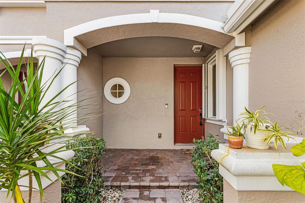 A front entryway features a red door, a circular window, and two white columns — 3345 ANTICA STREET, FORT MYERS, FL