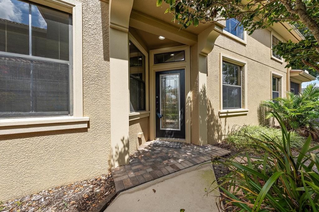 A tan stucco house exterior features a front door with a decorative glass insert — 8241 ACADIAN LANE, SEMINOLE, FL
