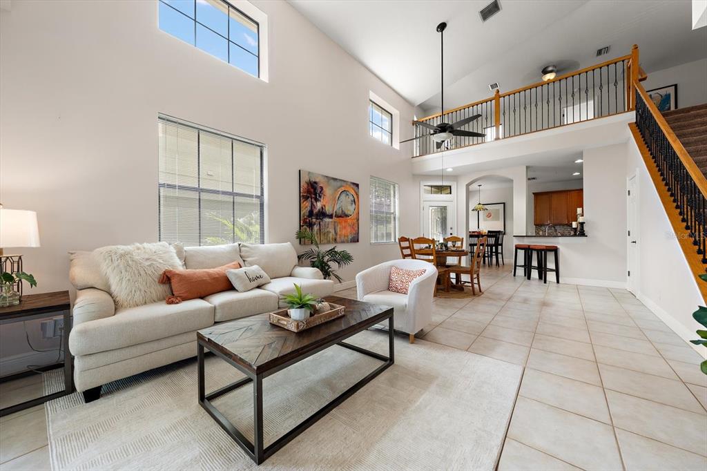 A living room with high ceilings, a staircase, and an open-concept kitchen and dining area — 8241 ACADIAN LANE, SEMINOLE, FL