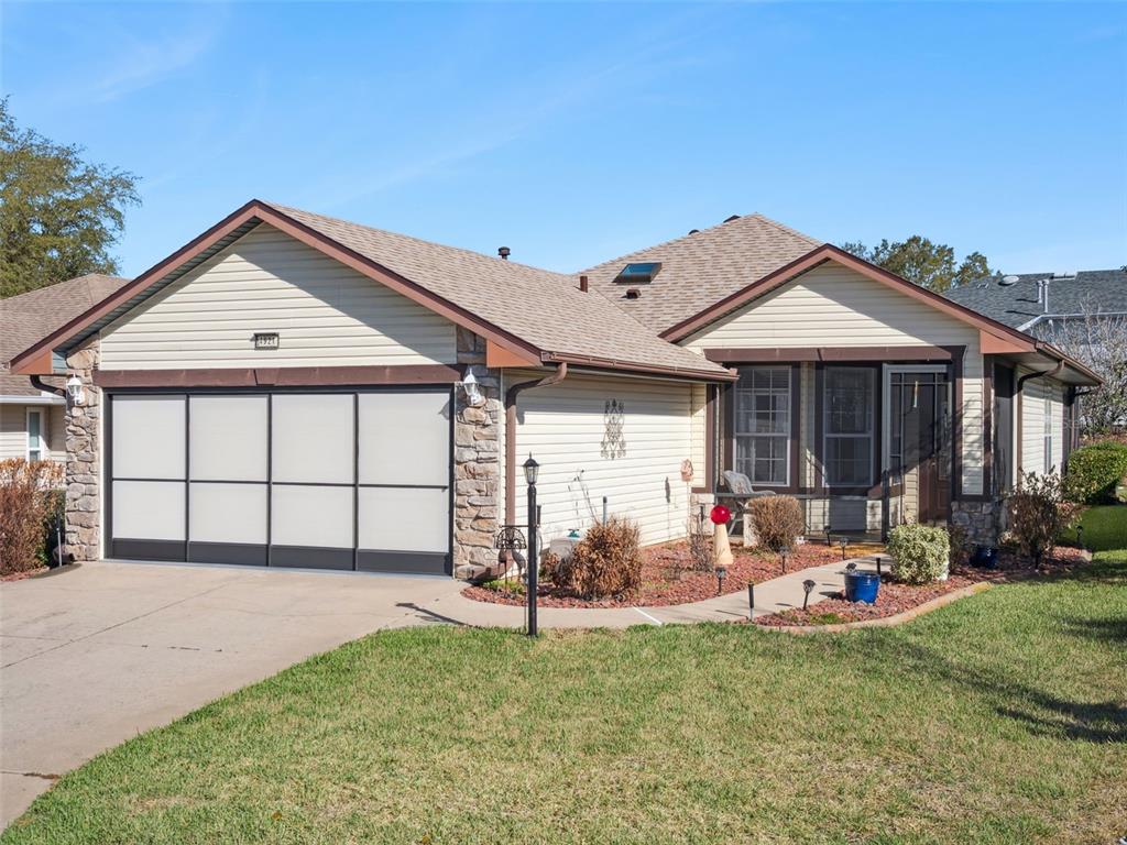A single-story house with a two-car garage, stone accents, and a front walkway — 4921 GLEN COE STREET, LEESBURG, FL