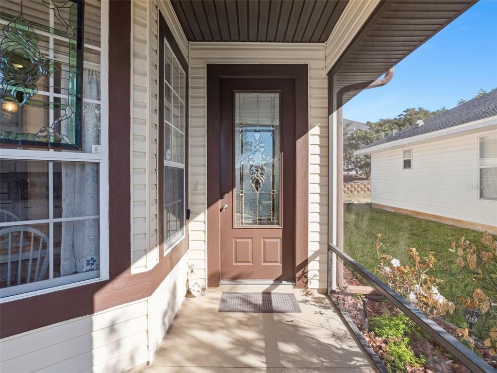A covered front porch features a brown door with a decorative glass insert — 4921 GLEN COE STREET, LEESBURG, FL