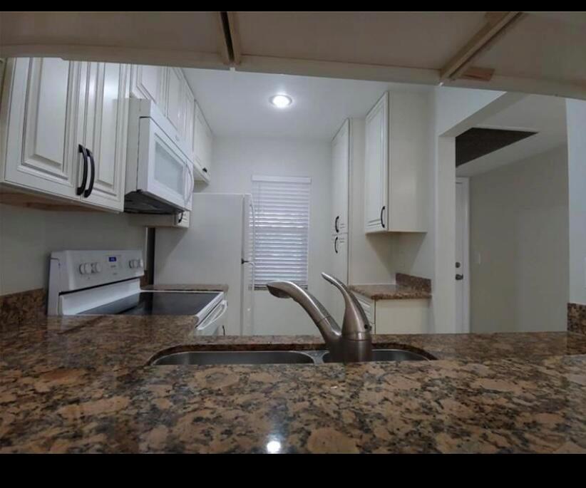 A kitchen features white cabinets, granite countertops, a double sink, and white appliances — 9903 Three Lakes Circle, Boca Raton FL 33428, BOCA RATON, FL