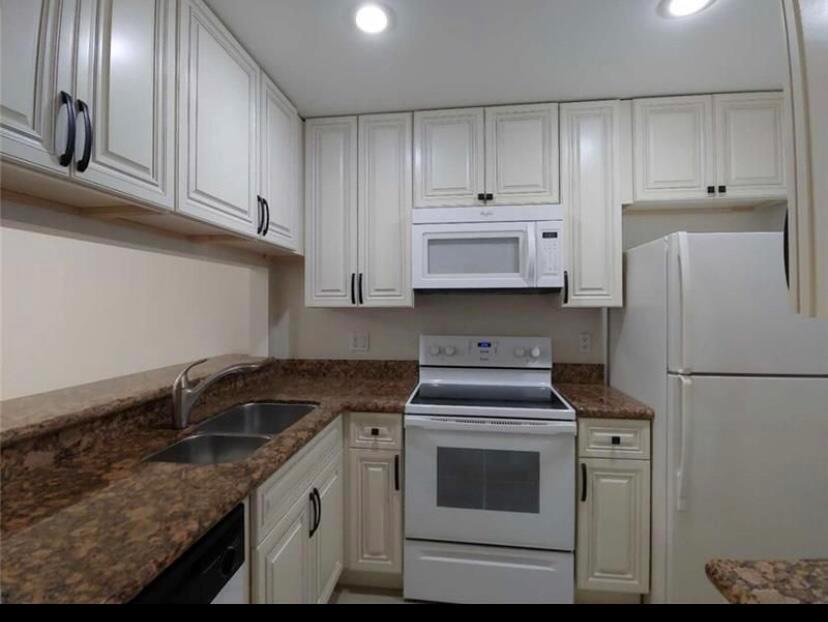 A kitchen features white cabinets, granite countertops, a white stove, and a white refrigerator — 9903 Three Lakes Circle, Boca Raton FL 33428, BOCA RATON, FL
