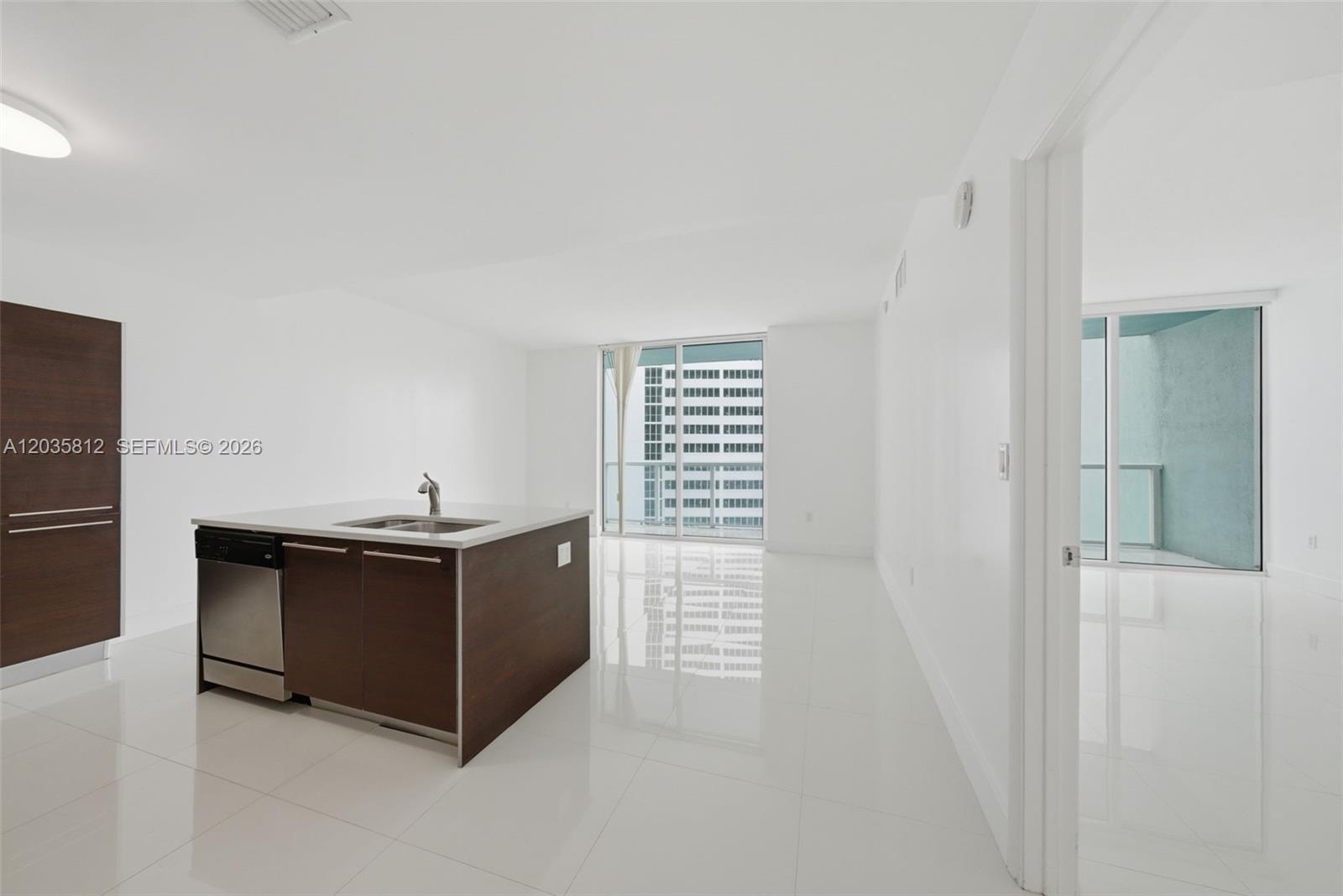 A modern kitchen island with a stainless steel dishwasher sits in a bright, white room — 1900 N Bayshore Dr # 2207, Miami FL 33132, MIAMI, FL