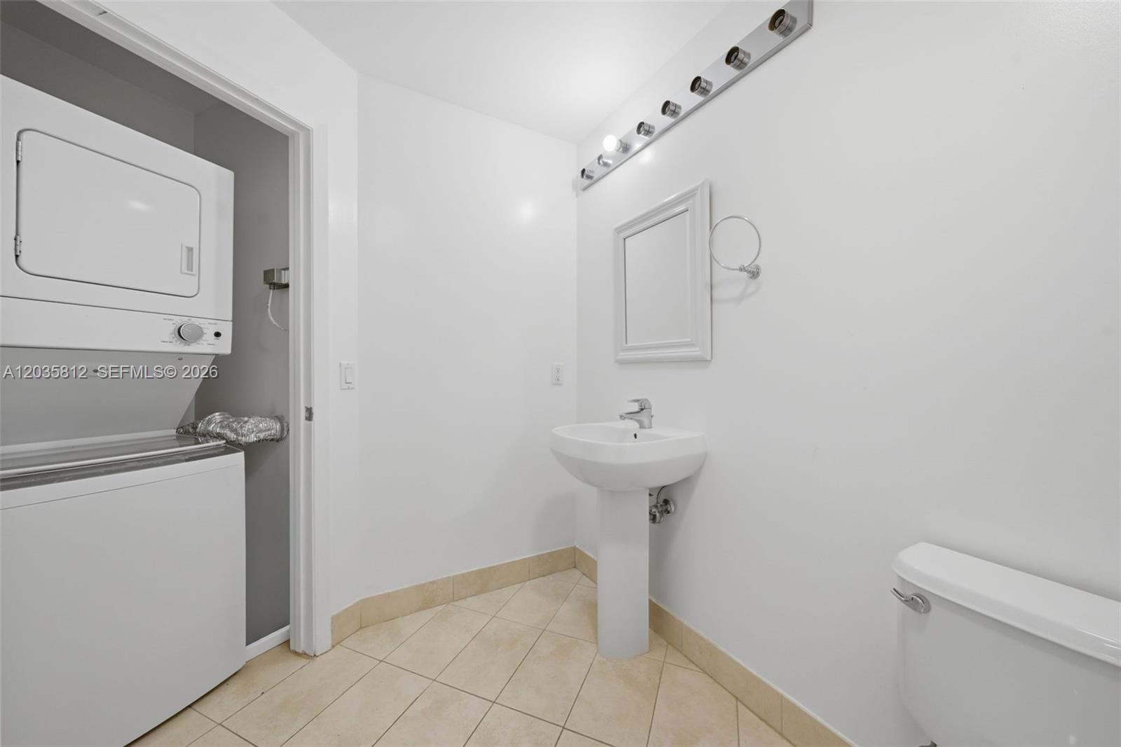 A bathroom features a pedestal sink, a toilet, and a stacked washer and dryer unit — 1900 N Bayshore Dr # 2207, Miami FL 33132, MIAMI, FL