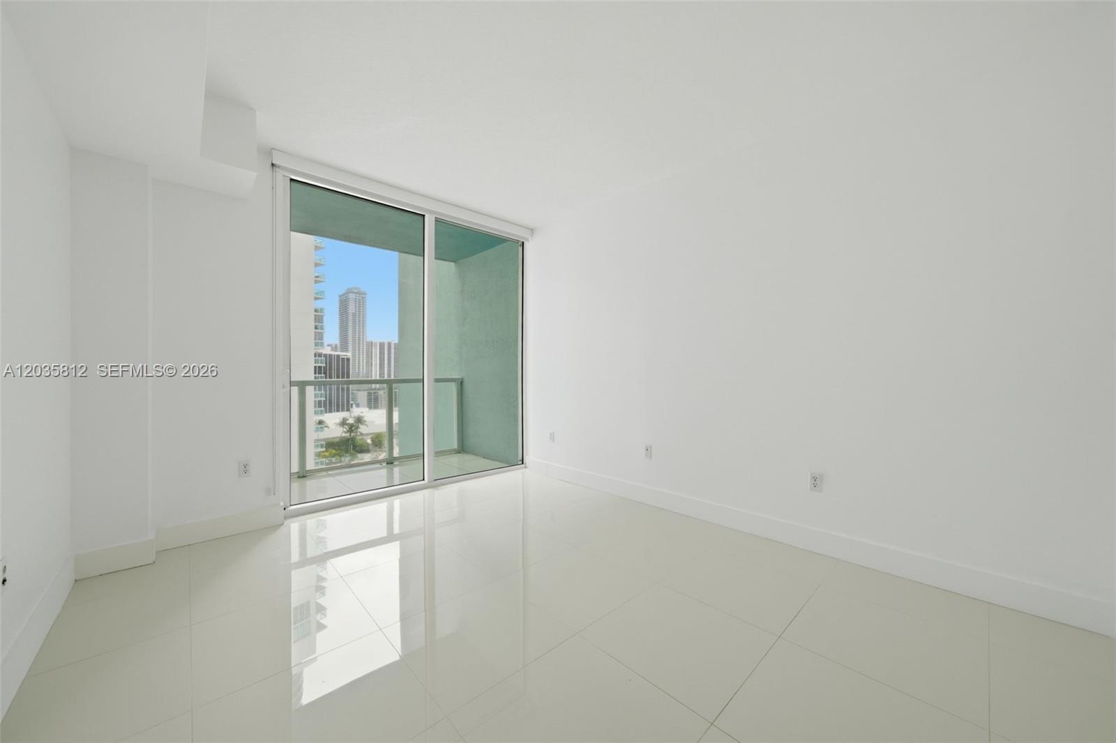An empty room with white walls, glossy tile floors, and a sliding glass balcony door — 1900 N Bayshore Dr # 2207, Miami FL 33132, MIAMI, FL