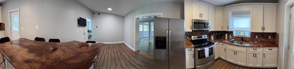 A kitchen island with a dark, textured countertop sits in a room with wood flooring — 2940 LAKE MARGARET DRIVE, ORLANDO, FL