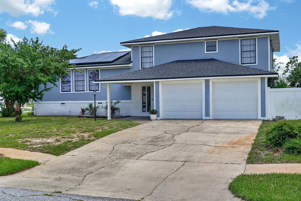 A two-story blue house with a two-car garage, solar panels, and a concrete driveway — 600 SEA GULL COURT, EDGEWATER, FL
