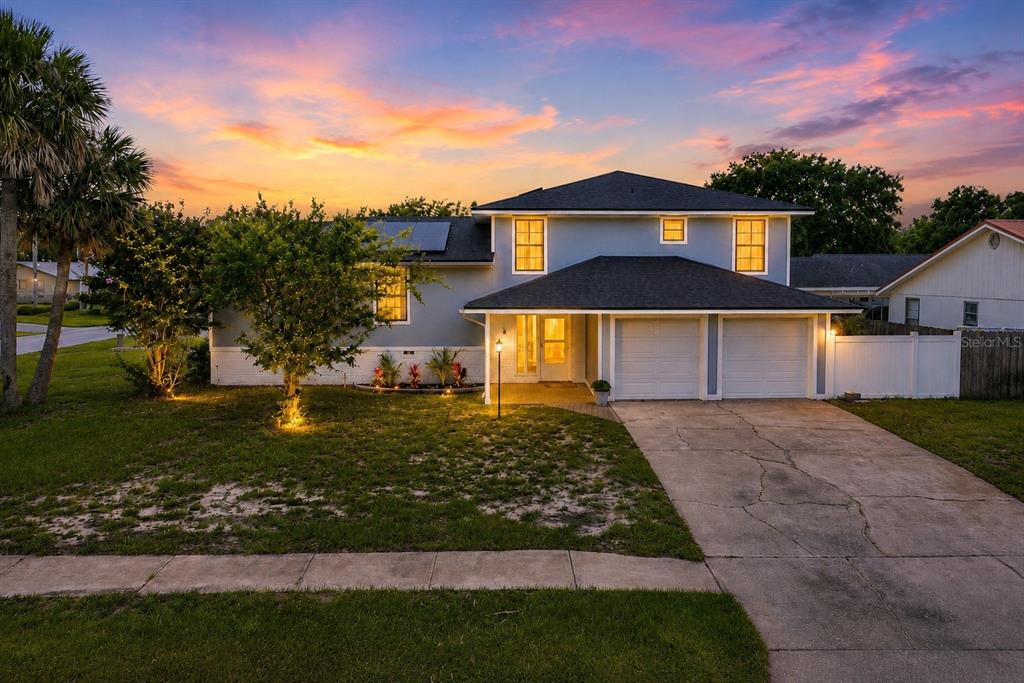 A two-story blue house with a two-car garage and a paved driveway at sunset — 600 SEA GULL COURT, EDGEWATER, FL