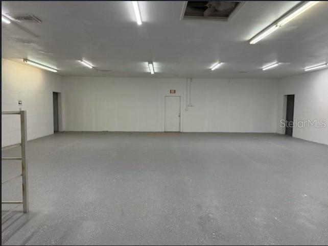 An empty, wide-open commercial space with white walls, gray speckled flooring, and overhead fluorescent lighting — 2525 N BETHLEHEM ROAD UNIT A, PLANT CITY, FL