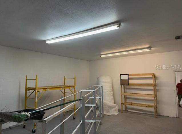 An interior view of a garage with white walls, two fluorescent lights, and storage equipment — 2525 N BETHLEHEM ROAD UNIT A, PLANT CITY, FL