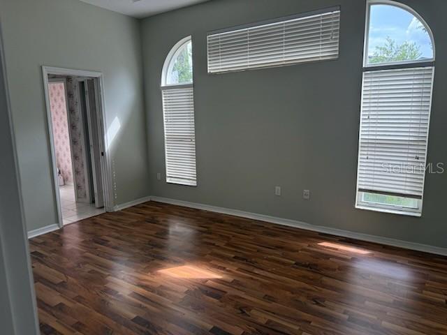 An empty room with wood-look flooring, light gray walls, and several windows with blinds — 1102 STILLWATER DRIVE, DELAND, FL