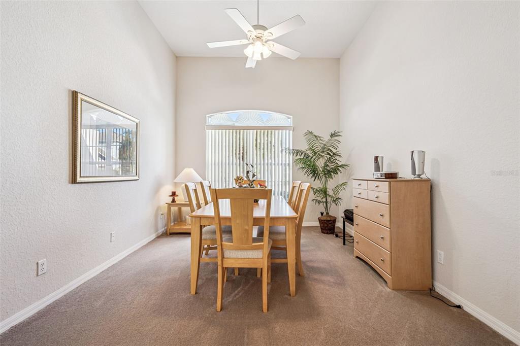 A dining room with a wooden table, chairs, carpeted flooring, and a ceiling fan — 718 CORVINA DRIVE, DAVENPORT, FL