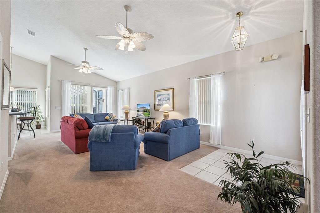 A living room features carpeted flooring, two blue sofas, a red sofa, and ceiling fans — 718 CORVINA DRIVE, DAVENPORT, FL