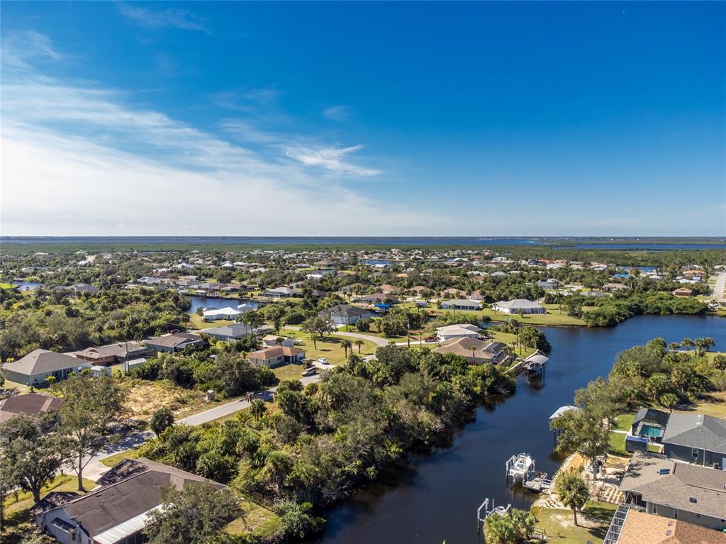 An aerial view shows a residential neighborhood with houses situated along a winding canal — 17324, 17332, 17340 GULFSPRAY CIRCLE, PORT CHARLOTTE, FL