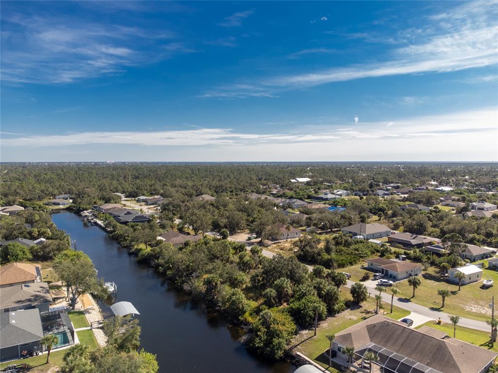 An aerial view shows a canal flowing through a residential neighborhood with houses and trees — 17324, 17332, 17340 GULFSPRAY CIRCLE, PORT CHARLOTTE, FL