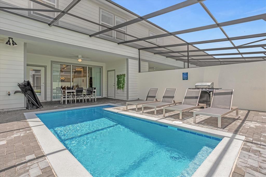 A screened-in patio features a swimming pool, lounge chairs, and an outdoor dining area — 4310 LANA AVENUE, DAVENPORT, FL