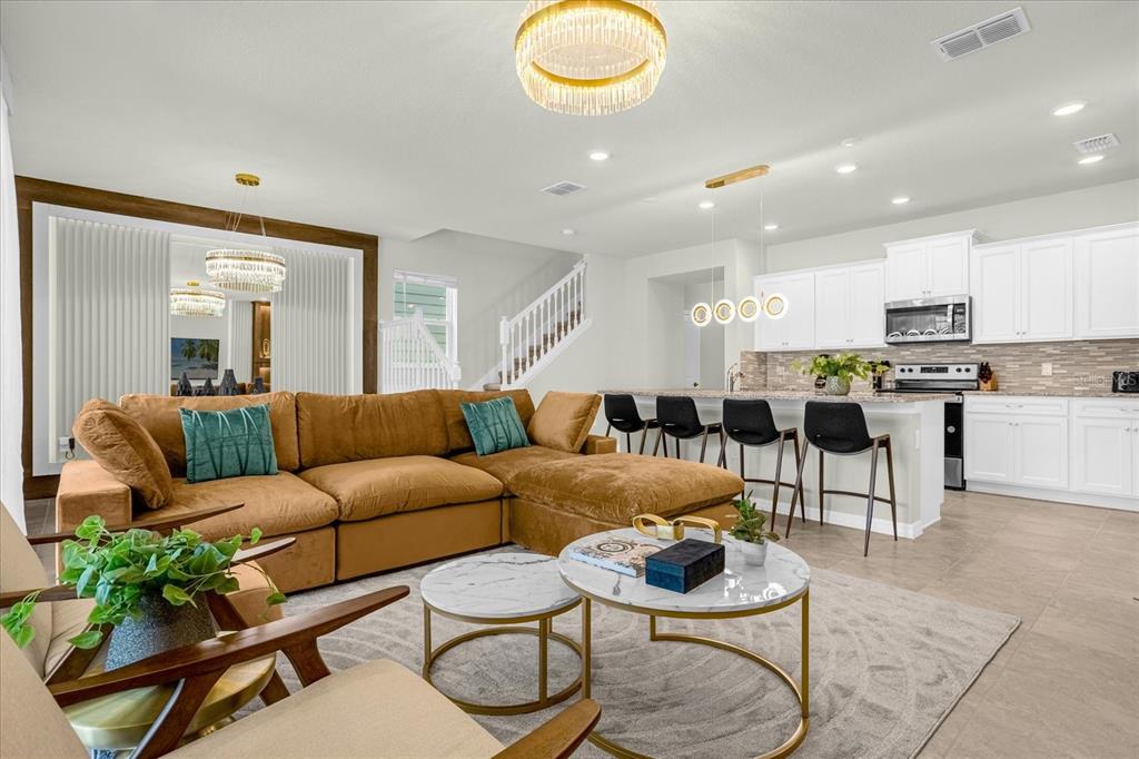 An open-concept living room and kitchen featuring a brown sectional sofa and white cabinetry — 4310 LANA AVENUE, DAVENPORT, FL