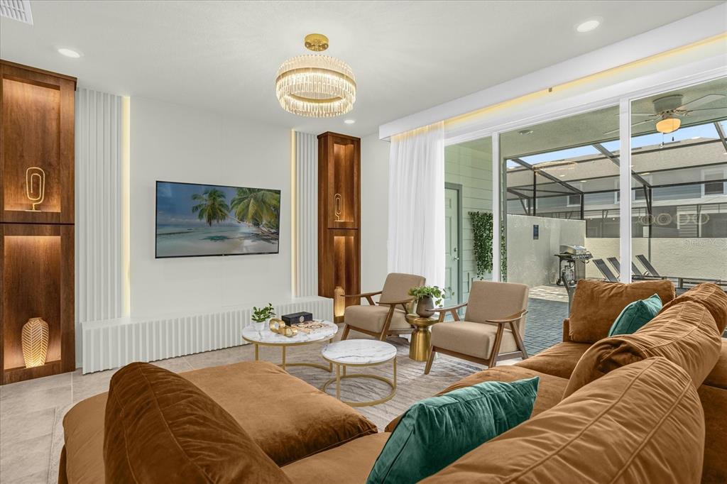 A modern living room features a brown sectional, two armchairs, and built-in wooden shelving units — 4310 LANA AVENUE, DAVENPORT, FL