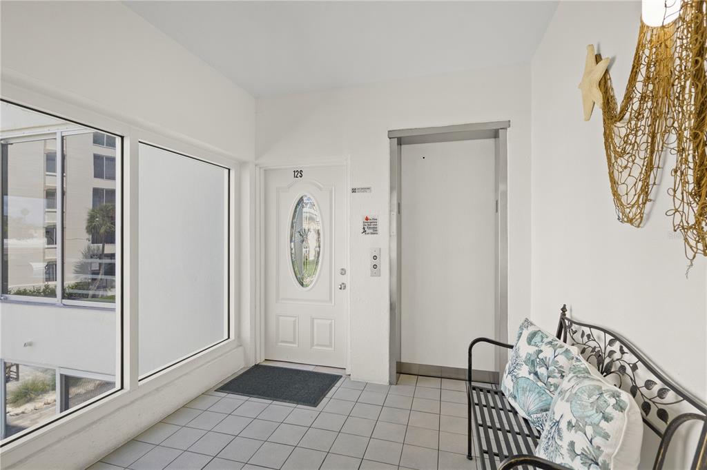 A white door labeled 12S sits next to an elevator in a tiled entryway — 6146 MIDNIGHT PASS ROAD UNIT 12S, SARASOTA, FL