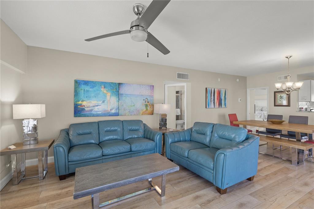 A living room features blue leather sofas, a wooden coffee table, and a dining area — 6146 MIDNIGHT PASS ROAD UNIT 12S, SARASOTA, FL
