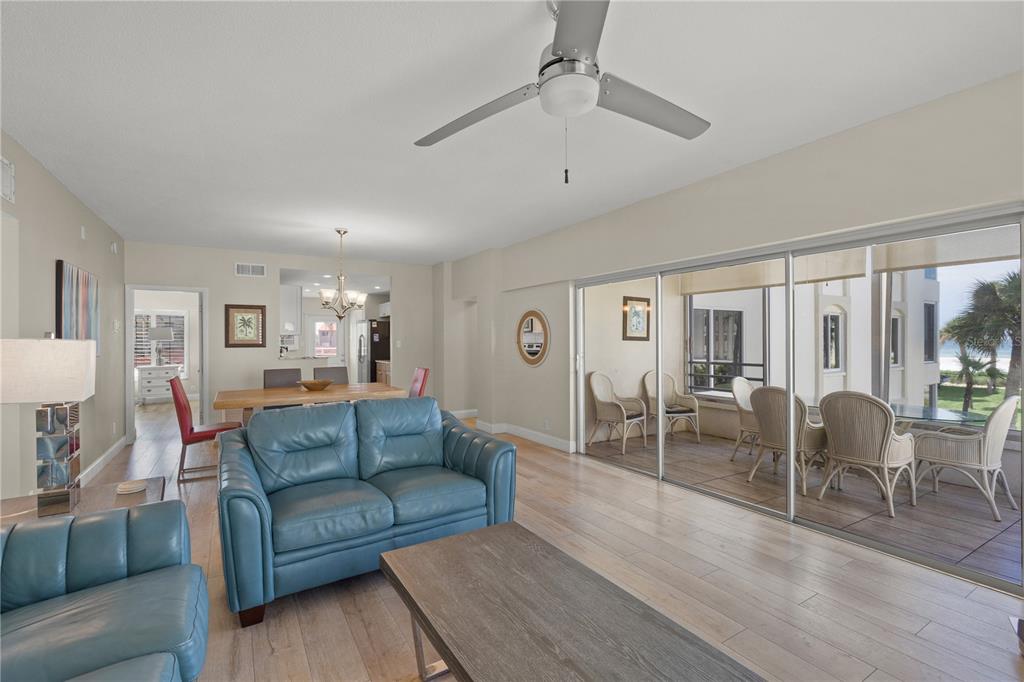 A living room with blue leather sofas, a dining area, and a balcony overlooking the beach — 6146 MIDNIGHT PASS ROAD UNIT 12S, SARASOTA, FL
