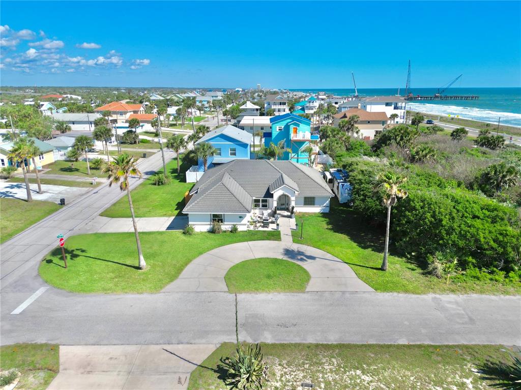 An aerial view shows a single-story house with a circular driveway near the ocean — 112 S 11TH STREET, FLAGLER BEACH, FL