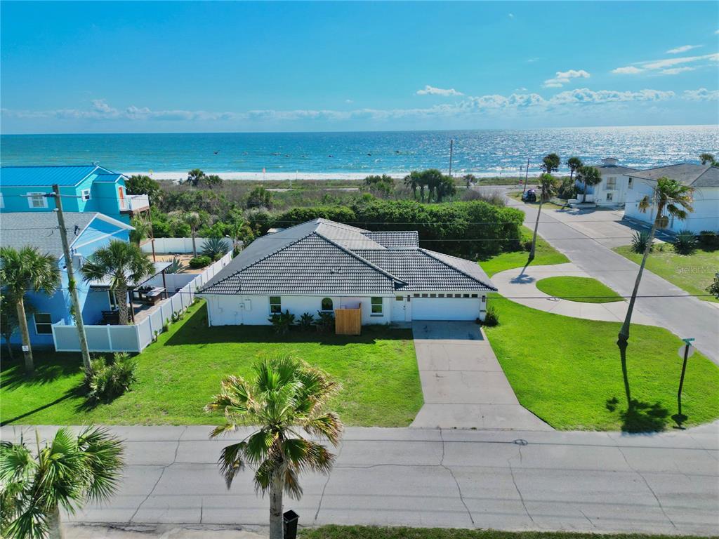 An aerial view shows a white house with a gray tile roof near the ocean — 112 S 11TH STREET, FLAGLER BEACH, FL
