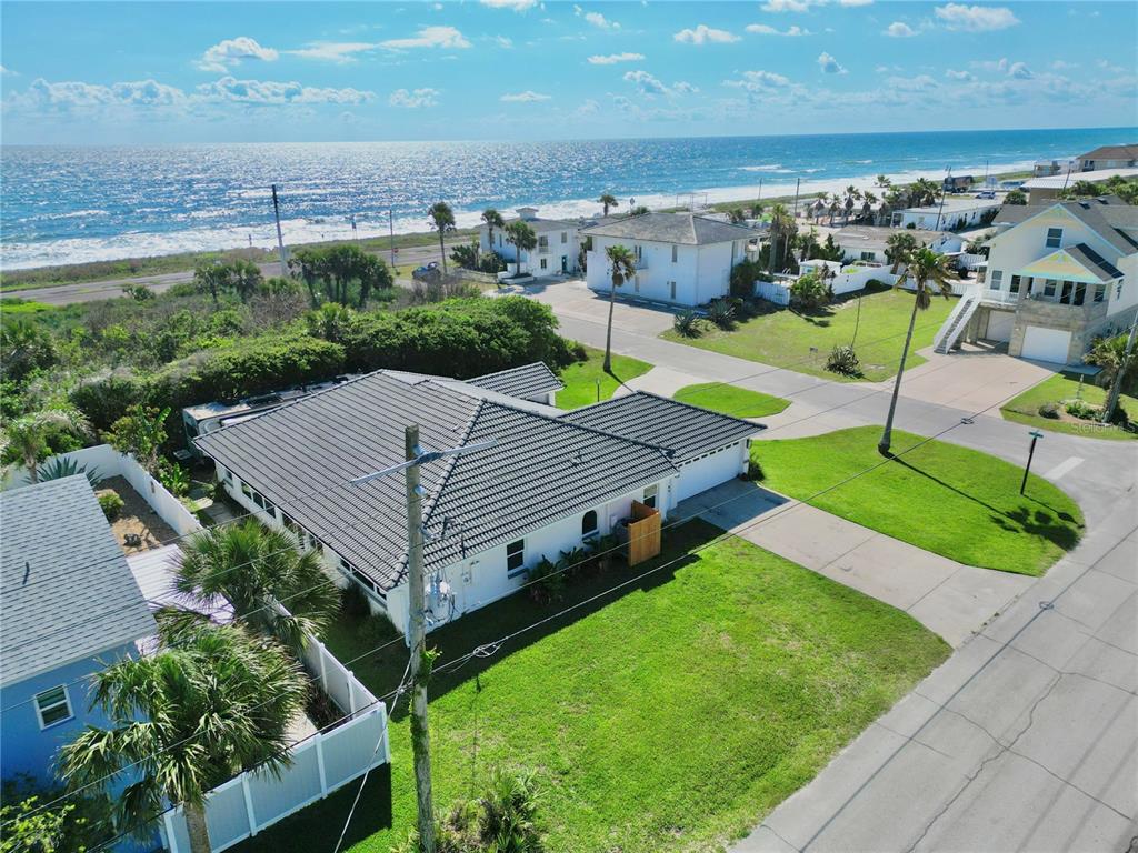 An aerial view shows a white house with a dark roof near a coastal beach — 112 S 11TH STREET, FLAGLER BEACH, FL