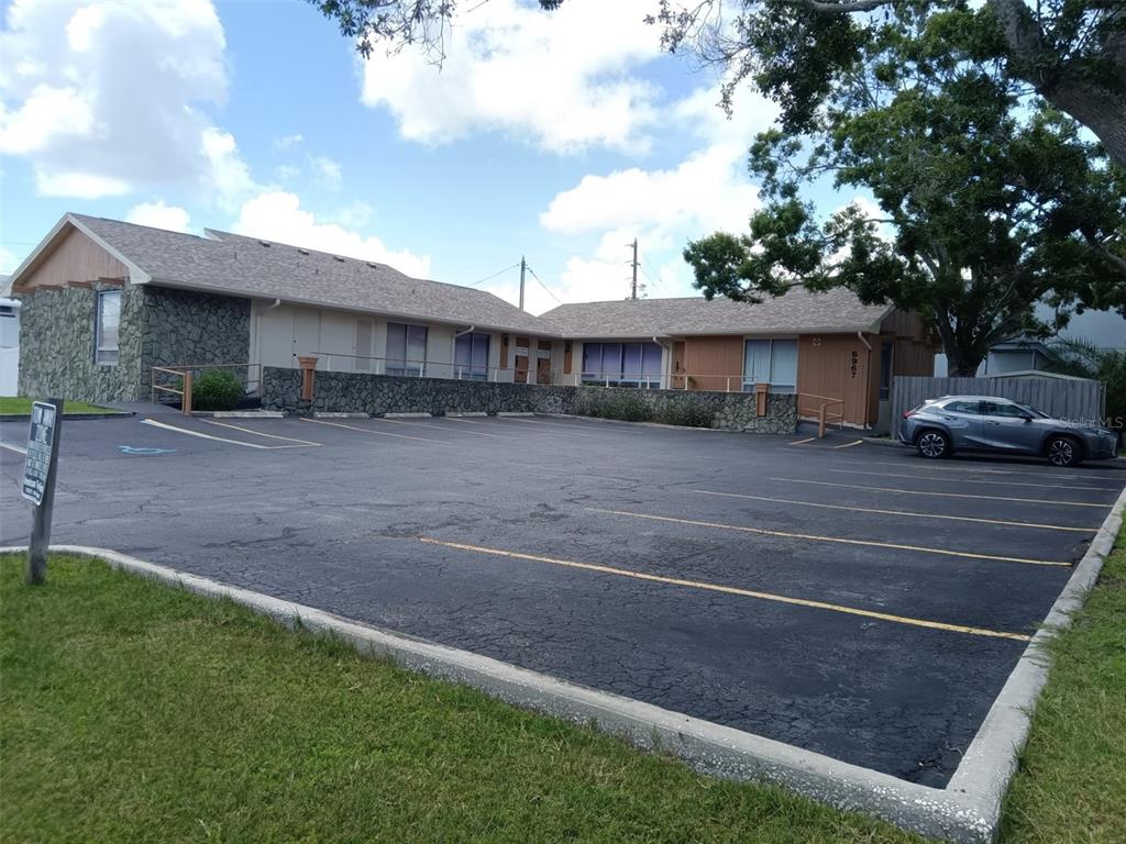 A single-story commercial building with a stone facade and an adjacent asphalt parking lot — 6967 SUNSET DRIVE S, ST PETERSBURG, FL